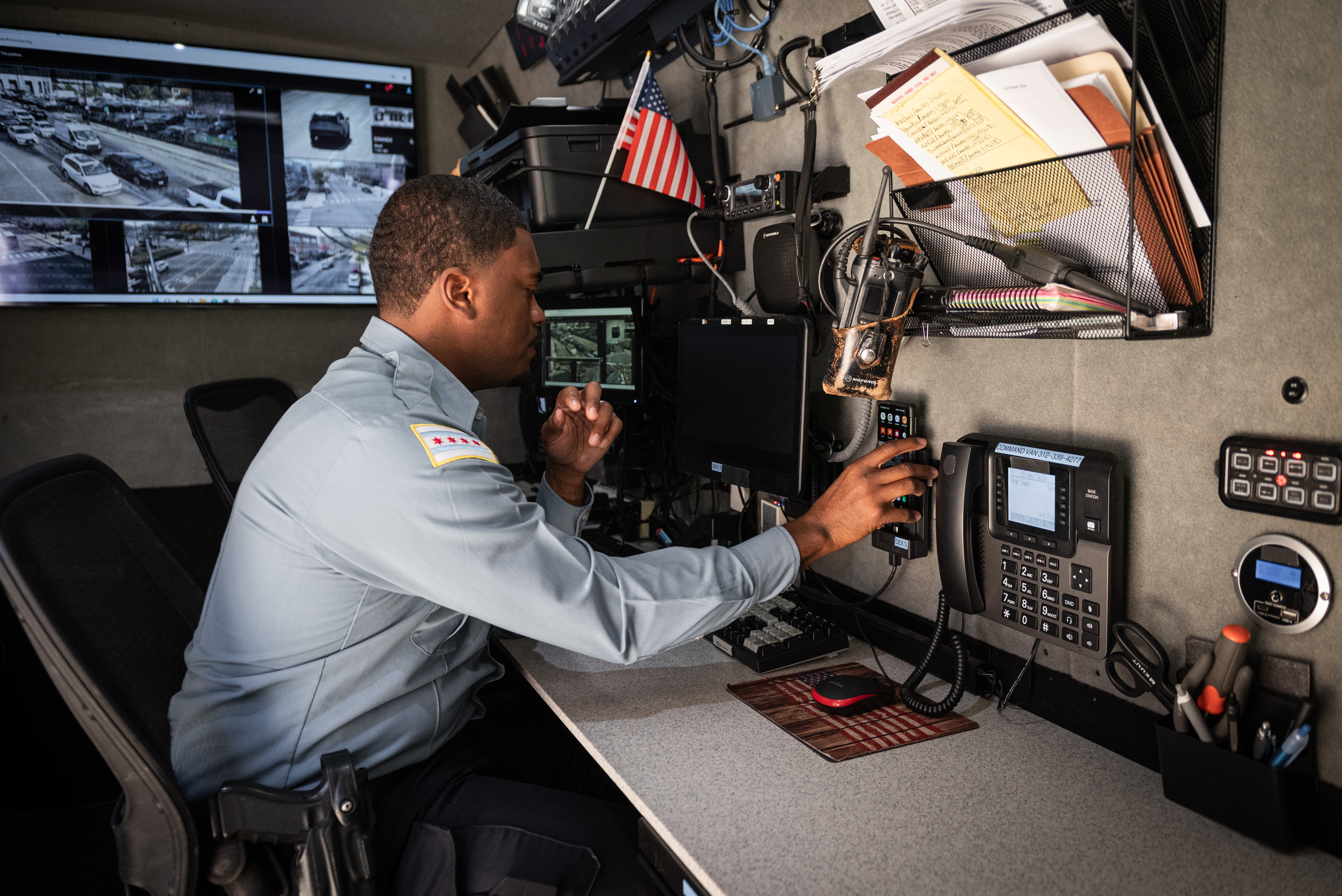 A Chicago police officer in a mobile command center, monitoring surveillance feeds and operating communication equipment.